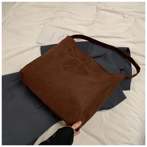 Detail of a brown suede tote bag with matte texture on a white fabric background