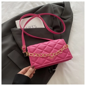 Detail of rose red quilted crossbody bag featuring gold chain and fashion lettering