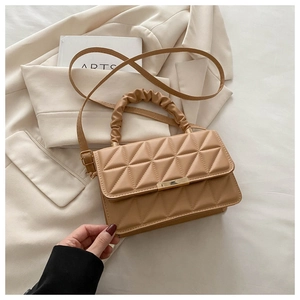 Close-up of beige quilted crossbody bag with gold metal clasp and pleated handle