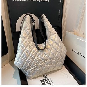 Close-up of quilted silver puffer tote bag with glossy metallic finish and black strap