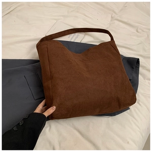 Detail of a large brown matte suede tote bag showing texture and fixed wide shoulder strap
