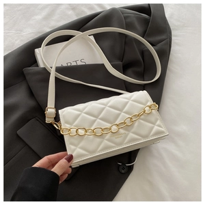 Detail of cream quilted mini square bag with chunky gold chain and black blazer styling