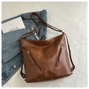 Dettaglio borsa vintage in pelle marrone con due tasche frontali a cerniera e tracolla regolabile