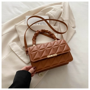 Close-up of caramel brown quilted handbag with pleated handle and gold hardware detail