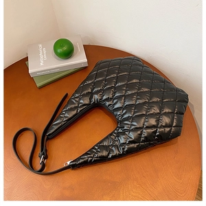 Detail view of black quilted hobo bag with glossy finish on a wooden table