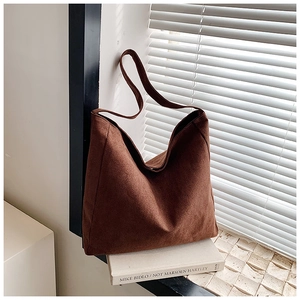 Macro detail of the dark brown suede texture and wide strap on a retro tote bag