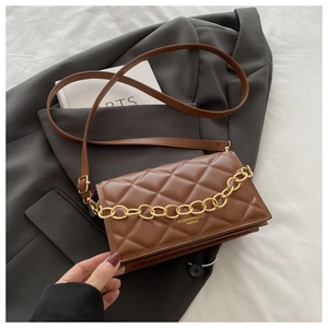 Close-up of brown quilted crossbody bag with gold chain strap and detailed stitching