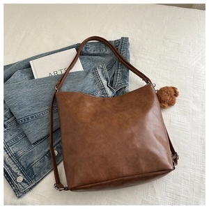 Dettaglio della borsa tote vintage in pelle PU marrone con ciondolo a forma di orso di peluche