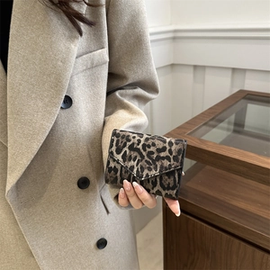 Piccolo portamonete a bustina con stampa leopardata tenuto da una modella in blazer