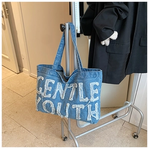 Détail de la broderie Gentle Youth sur le sac cabas en denim délavé bleu clair