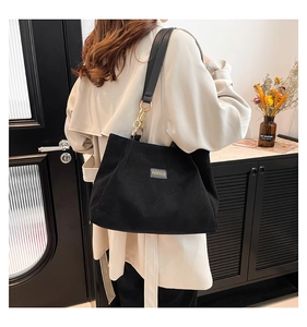 Détail du sac cabas en velours côtelé noir avec anneaux métalliques et étiquette