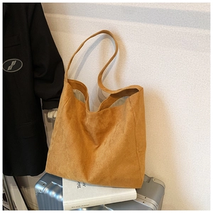 Macro shot of large mustard suede tote bag on a silver suitcase with textured material