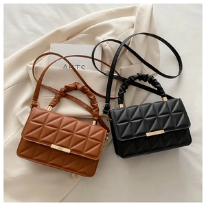 Detail view of quilted cross-body bags in black and brown with ruched handles and gold accents