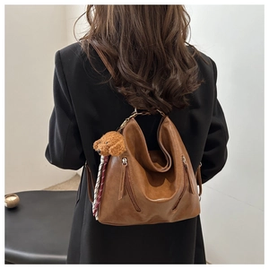 Dettaglio della borsa tote vintage in pelle marrone con cerniere e ciondolo a peluche