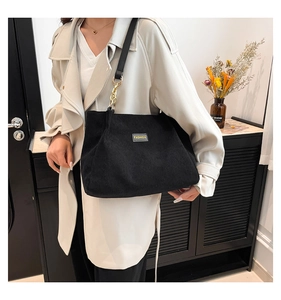 Détail du sac cabas en velours côtelé noir avec étiquette FASHION et anneau doré chic