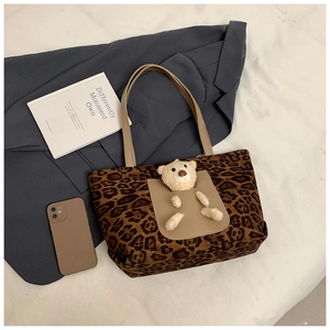 Close-up of leopard print tote bag featuring a plush bear charm and front pocket detail
