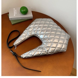 Detailed macro of silver quilted puffer hobo bag on a table with metallic finish