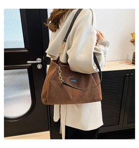 Sac cabas en velours côtelé marron avec lanières en cuir noir sur un mannequin