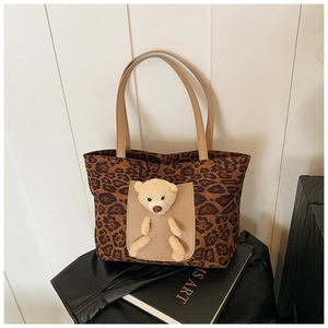 Close-up of leopard print tote bag featuring a cute 3D teddy bear plush in the front pocket
