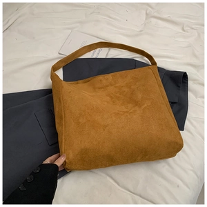 Detail of caramel suede tote bag with wide shoulder strap on navy and white fabric