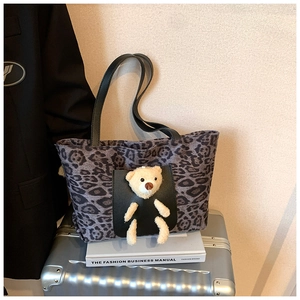 Detailed shot of leopard print canvas tote bag with black leather straps and plush bear