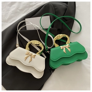 Detail of wavy flap texture and golden irregular handles on contrasting bow handbags