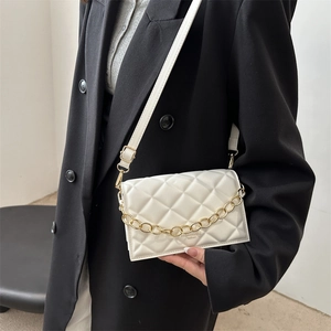 Quilted white crossbody bag with gold chain strap shown on model in black blazer
