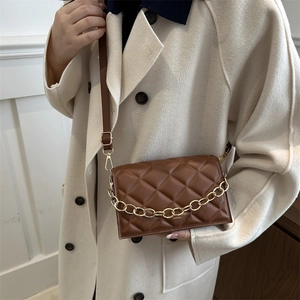 Brown quilted crossbody bag with gold chain worn on beige coat for women's fashion