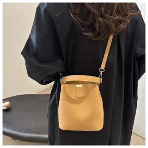 Dettaglio della borsa a secchiello color cammello con logo fashion e chiusura in metallo