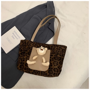 Detail view of leopard print tote bag with cute beige plush bear on the outer pocket