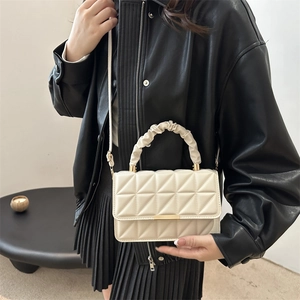 Quilted cream crossbody bag with textured handle and gold hardware on a model