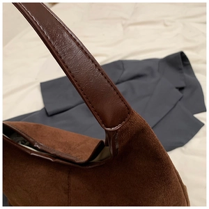 Detailopname van vintage bruine matte draagtas met suède textuur en lederen riemverbinding