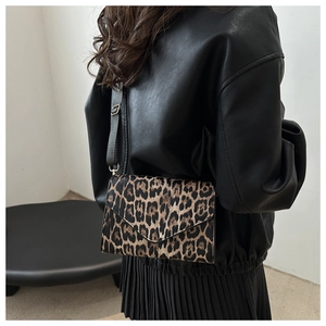 Leopard print crossbody bag with wide strap worn by a model in a minimalist setting