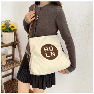 Chic beige canvas tote bag with brown logo shown on model in a minimalist lifestyle setting