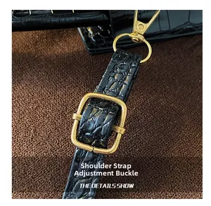 Macro shot of black crocodile embossed leather strap with vintage gold metal buckles