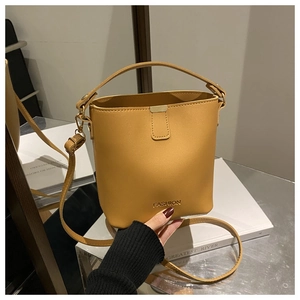 Dettaglio borsa a secchiello giallo senape con trama in pelle liscia e gancio per tracolla