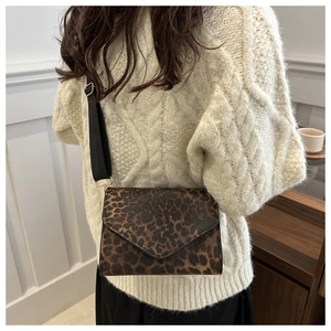 Détail du sac bandoulière léopard avec sangle en tissu porté sur un pull en maille