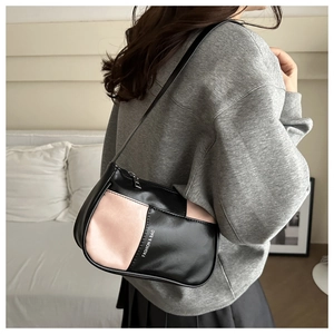 Detail of a color-block shoulder bag featuring pink and black panels and a slim strap