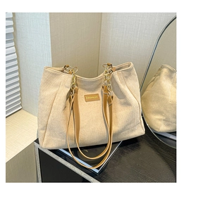 Détail du sac cabas en velours côtelé beige avec poignée en cuir brun et chaîne