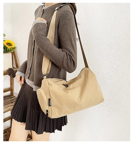 Detail of beige nylon crossbody bag with adjustable strap and fashion label on side