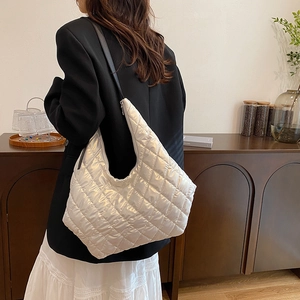 Quilted silver shoulder bag with pearl finish and black leather strap worn by a model
