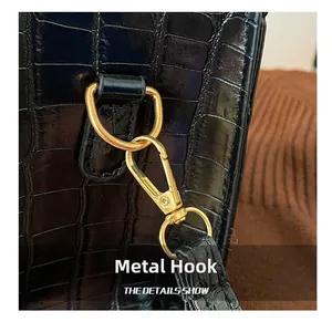 Detailed macro view of black crocodile pattern leather bag with gold lobster clasp hardware
