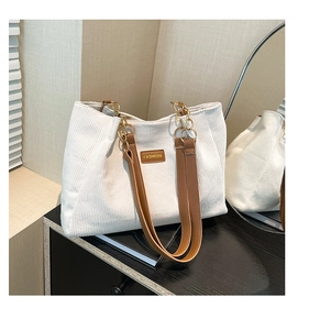 Gros plan du sac cabas en velours côtelé blanc avec bandoulière cuir marron et chaîne