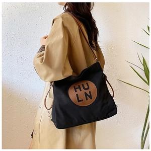 Detail of black canvas tote bag with brown leather patch and shoulder strap for daily use