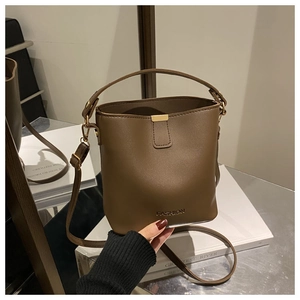 Dettaglio di una borsa a secchiello in ecopelle marrone scuro con fibbie dorate e logo
