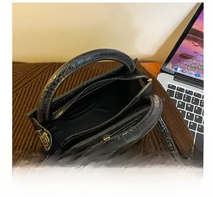 Interior view of black crocodile pattern handbag with zipper pockets and gold hardware