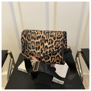 Détail d'un sac bandoulière léopard avec large sangle noire et boucle dorée chic