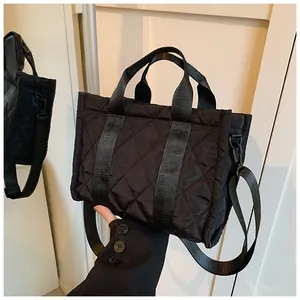 Detail of black quilted tote bag with reinforced handles and detachable shoulder strap