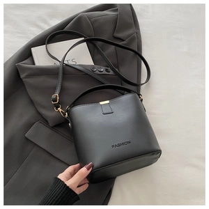 Dettaglio borsa a secchiello in pelle nera minimalista con chiusura dorata e logo moda