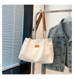 Détail du cabas en velours côtelé blanc avec anses en cuir et étiquette FASHION